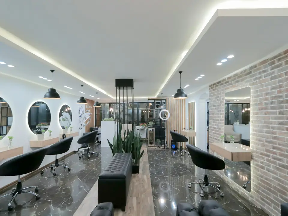 Peluquería moderna con espejos redondos y sillones negros, foto de ejemplo