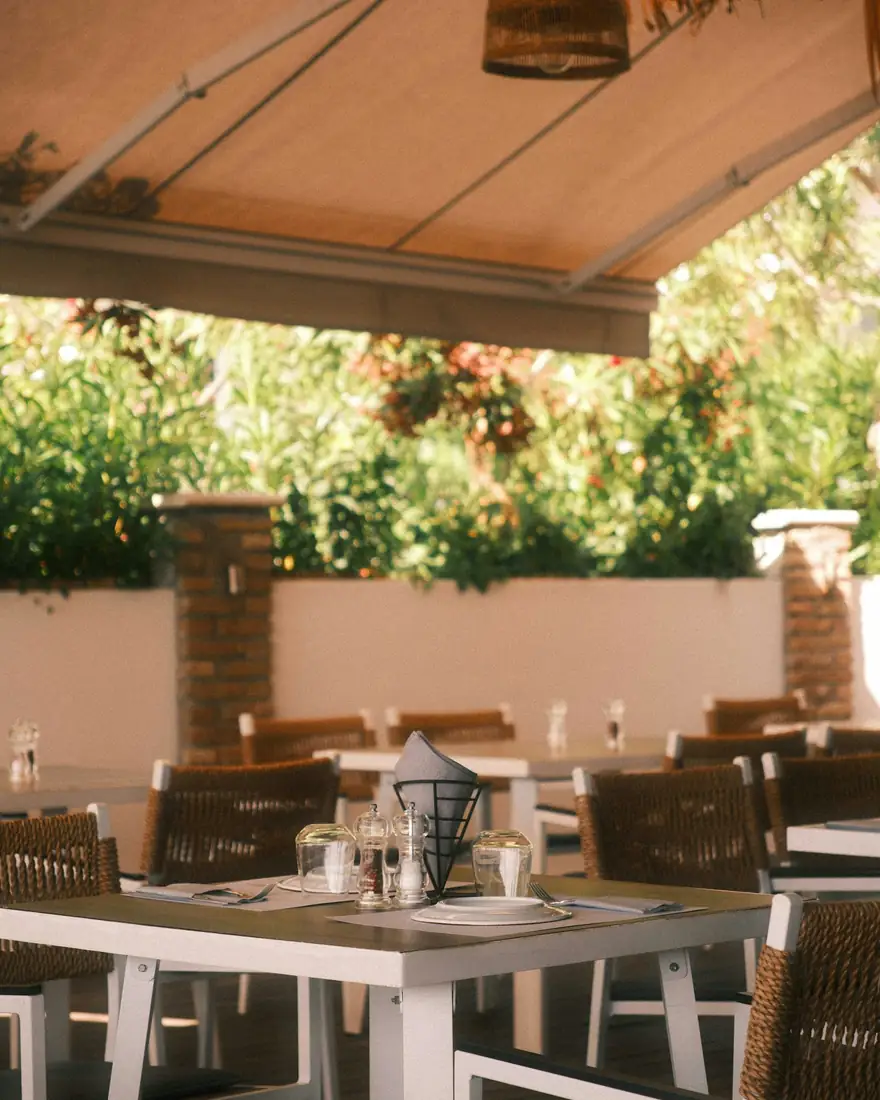 Terraza de un restaurante con mesas bajo un toldo, foto de ejemplo