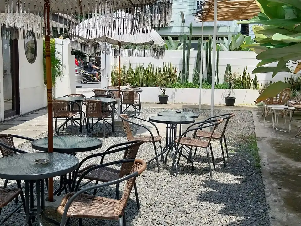 Patio de un restaurante con mesas y sombrillas, foto de ejemplo